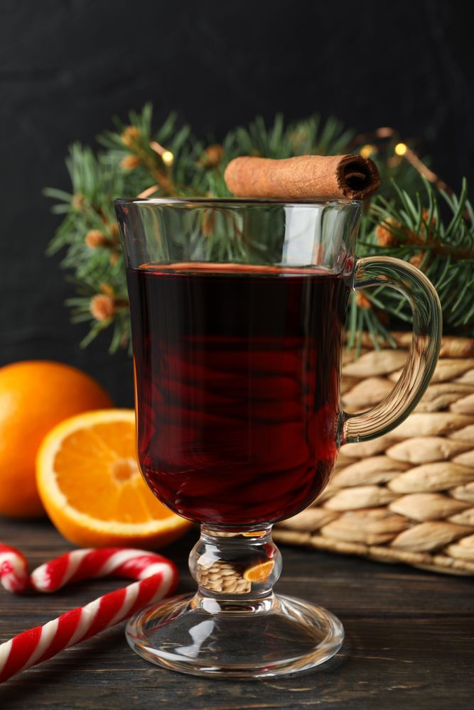 Glass of tasty mulled wine on decorated wooden background, space for text