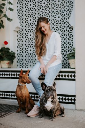 Stylish woman with dogs standing on street