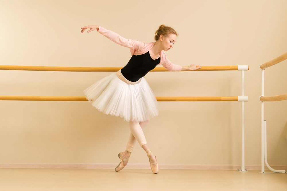 Ballet dancer stretches while holding barre