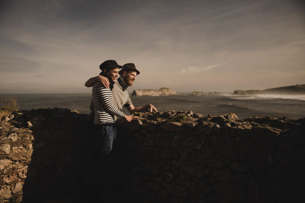 Man holding woman on hands near stones on shore