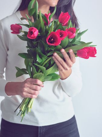 Crop female with bouquet of red tulips in hands