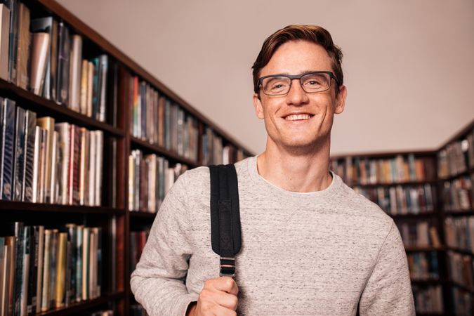 Portrait of young college student standing in library