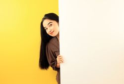 Young Indonesian Woman Wearing Kebaya, Peeking Behind Wall with Happy Expression