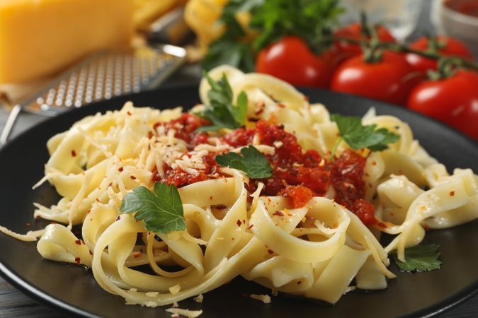 Ingredients for cooking and plate of tasty pasta, close up