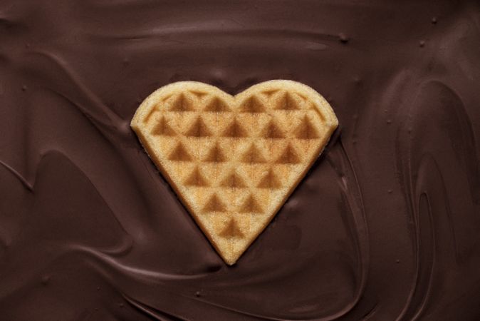 Heart-shaped waffle floating in melted chocolate