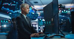Portrait of Stock Exchange Broker Working on Computer with Multi-Screen Workstation with Real-Time Stocks, Commodities and Exchange Market Charts.