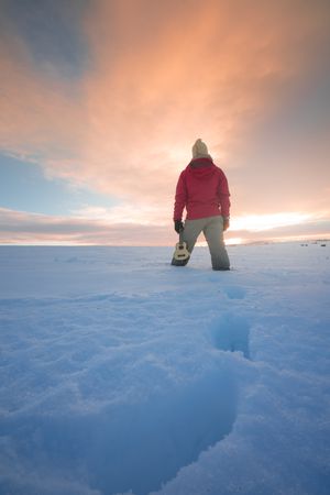 Traveler standing on snow against sunset sky