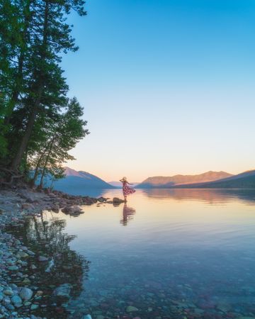 Woman wearing dress standing on rock near lake