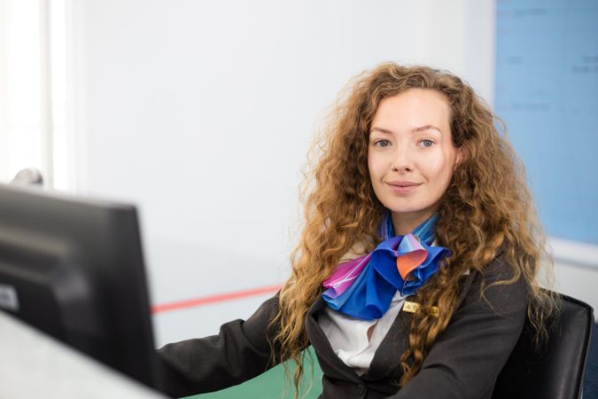 White woman in flight attendant uniform working at counter