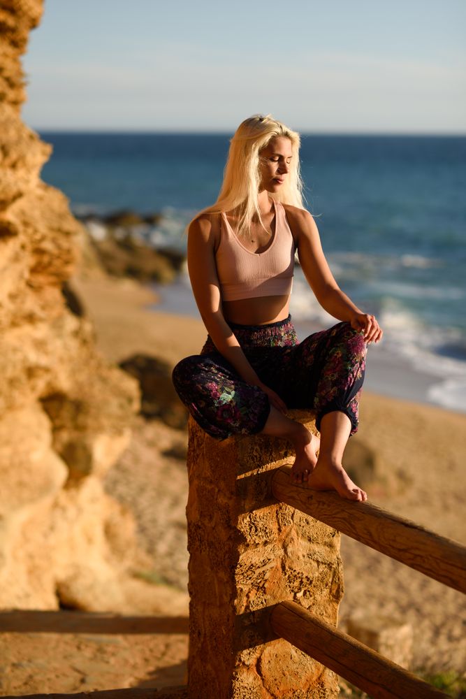 Blonde woman relaxing on post over looking beach with eyes closed