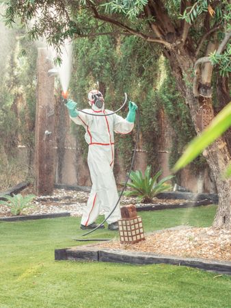 Fumigator in uniform spraying substance on garden