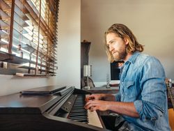 Thoughtful male playing synthesizer at home