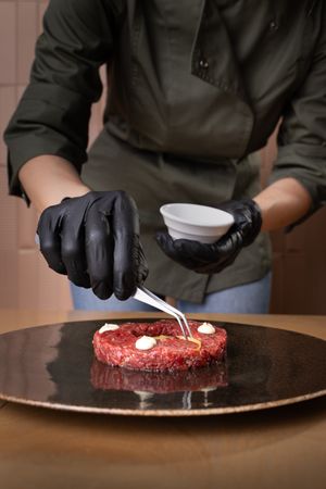 Chef plating beef tartare in fine dining restaurant kitchen