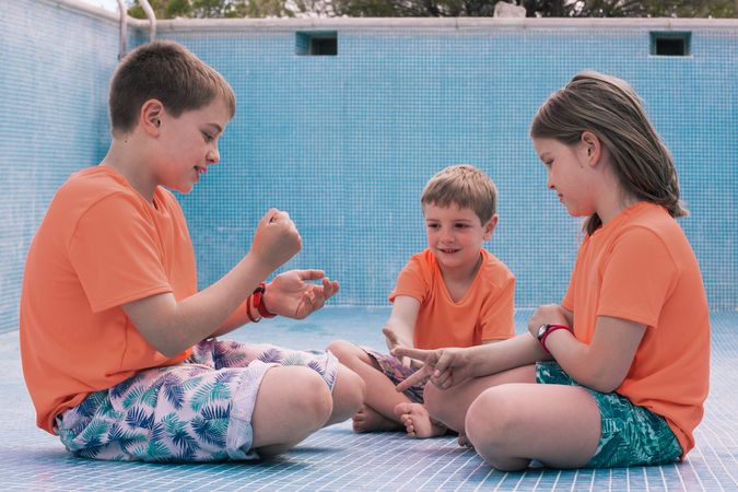 Children playing rock-paper-scissors in empty pool