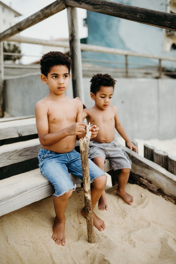 Black boys playing on beach while sitting in wood