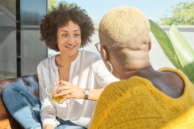 Cheerful Hispanic woman talking with ethnic friend at home