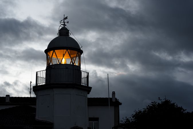 Shining lighthouse against cloudy sky