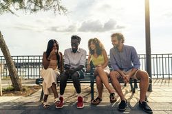 Group of friends laughing with a smartphone on a bench