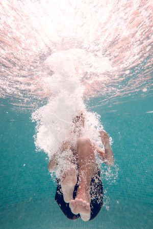 Anonymous boy diving underwater in pool