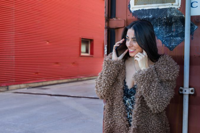 Trendy woman with smartphone near wall