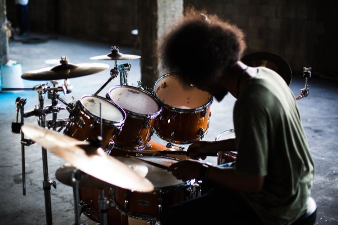 Back view of man playing drums in spacious garage