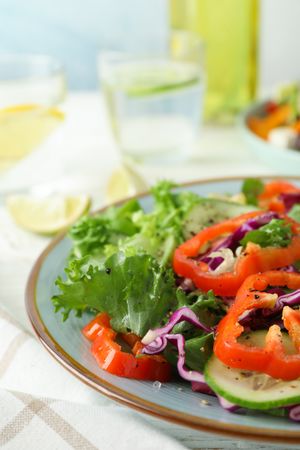 Plate with fresh salad on wooden table, space for text