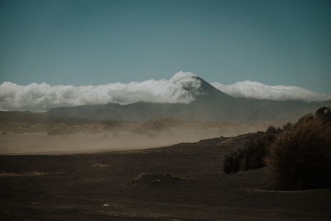 Dusty valley against high mountains in clouds