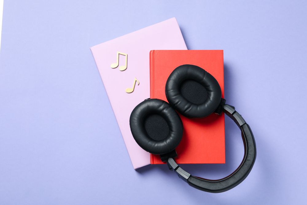 Concept of audiobook with books and headphones, top view