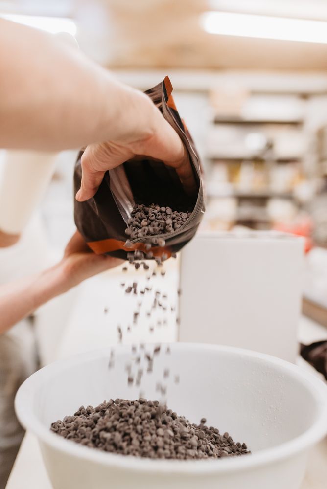 Crop confectioner spilling chocolate into bowl