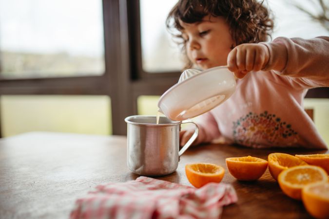 Little girl pouring homemade orange juice into cup