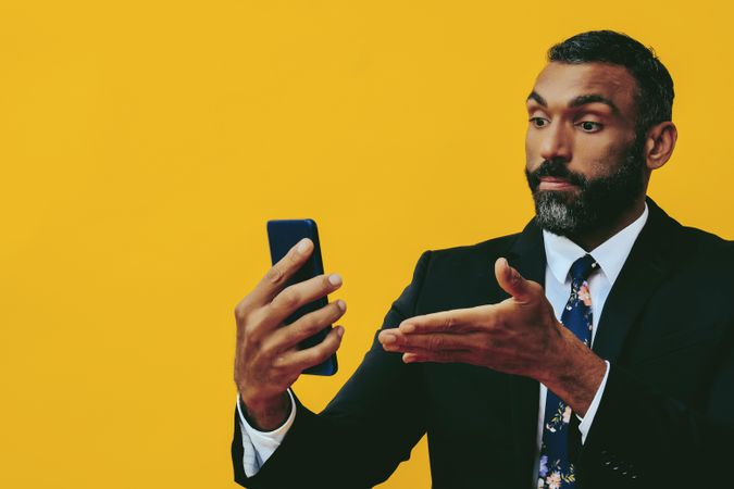 Serious Black businessman in suit gesturing at smartphone screen, copy space