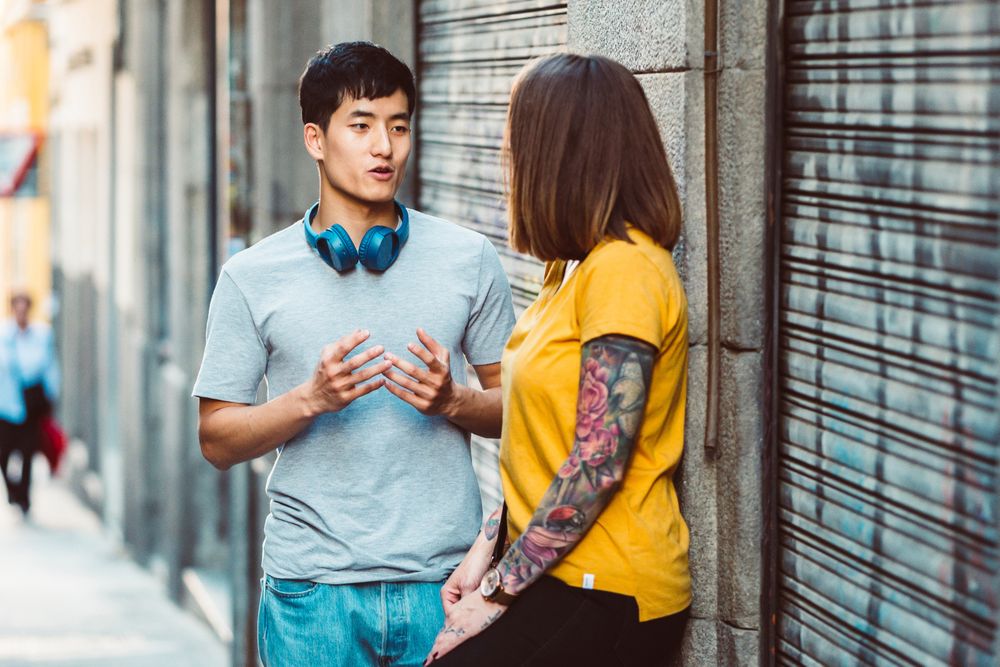 Joyful multiracial friends talking while standing on city street