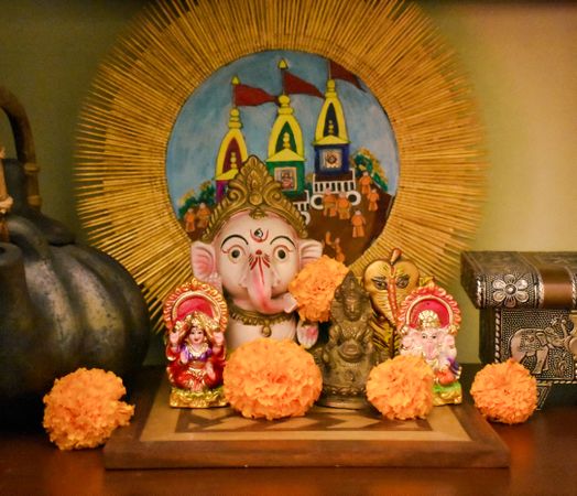 Hindu deity figurines surrounded by marigold flowers on table
