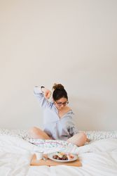 Young woman with breakfast on bed stretching out