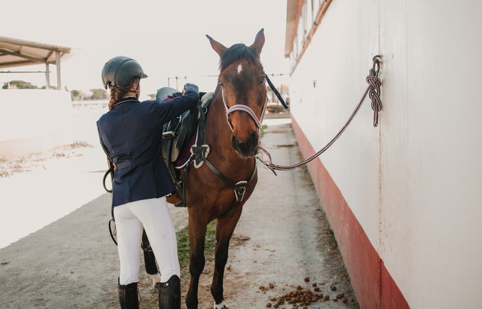 Woman in jockey outfit standing with horse