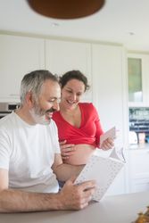 Smiling couple looking through book in kitchen
