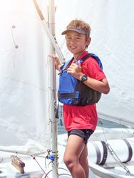 Smiling boy standing on sailboat