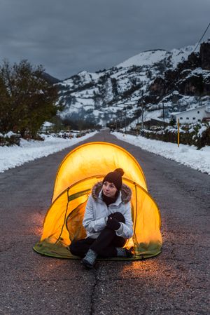 Woman sitting in open tent at twilight