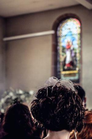 Back of woman’s head in church with stained glass