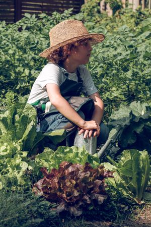 Adorable boy with watering can in garden