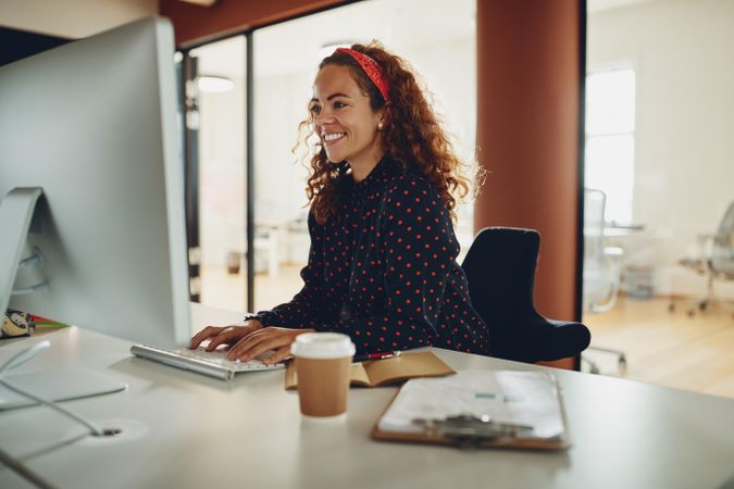 Woman with curly hair smiling at her work computer
