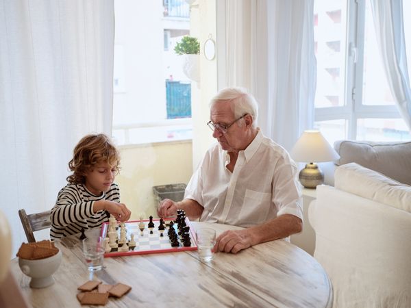 Older man teaching boy to play chess