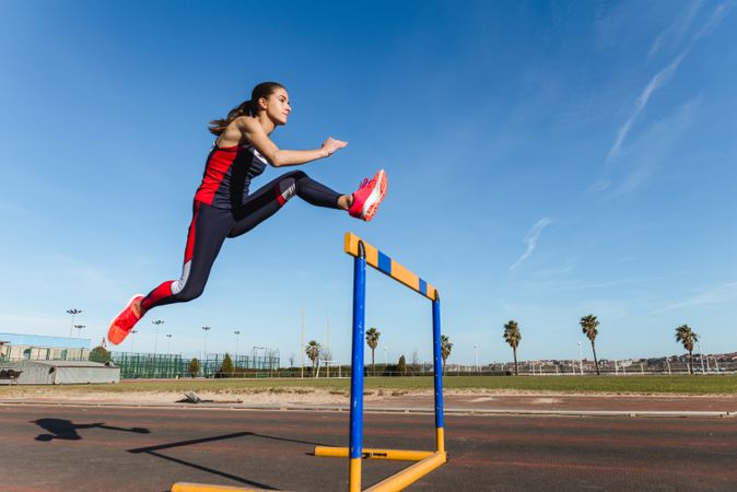Female athlete hurdling on stadium