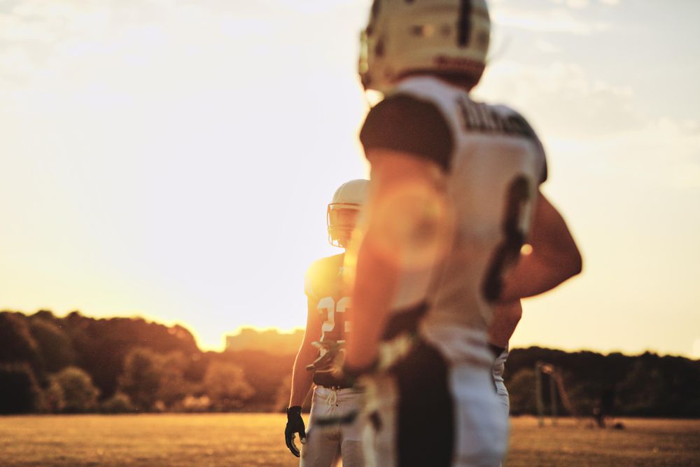 Footballers standing in the field at sunset
