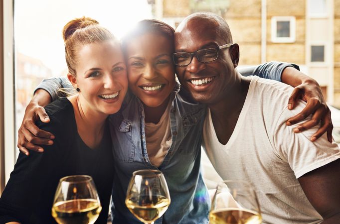 Portrait of three friends smiling with wine in a restaurant