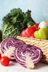 Wicker basket and vegetables on wooden background, close up