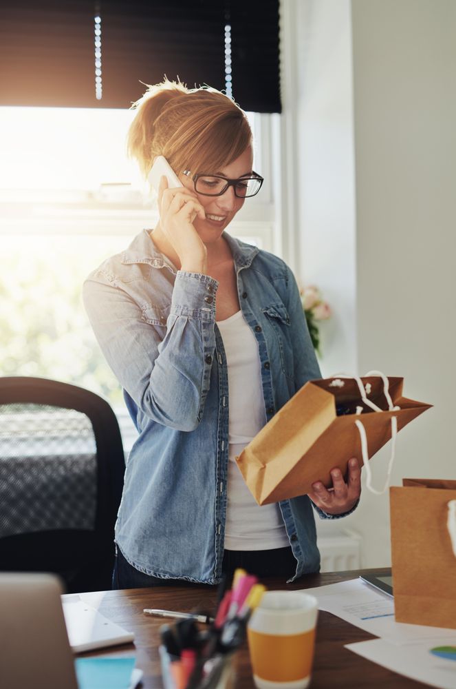 Happy woman on phone while looking at orders