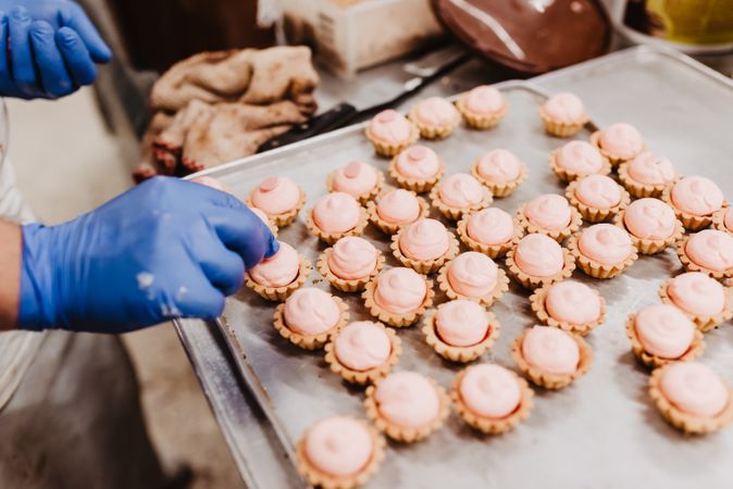 Anonymous baker decorating small cakes