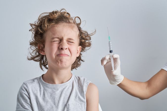 Boy closing eyes at syringe