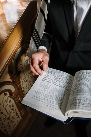 Cropped image of a man in dark suit standing and holding an open book